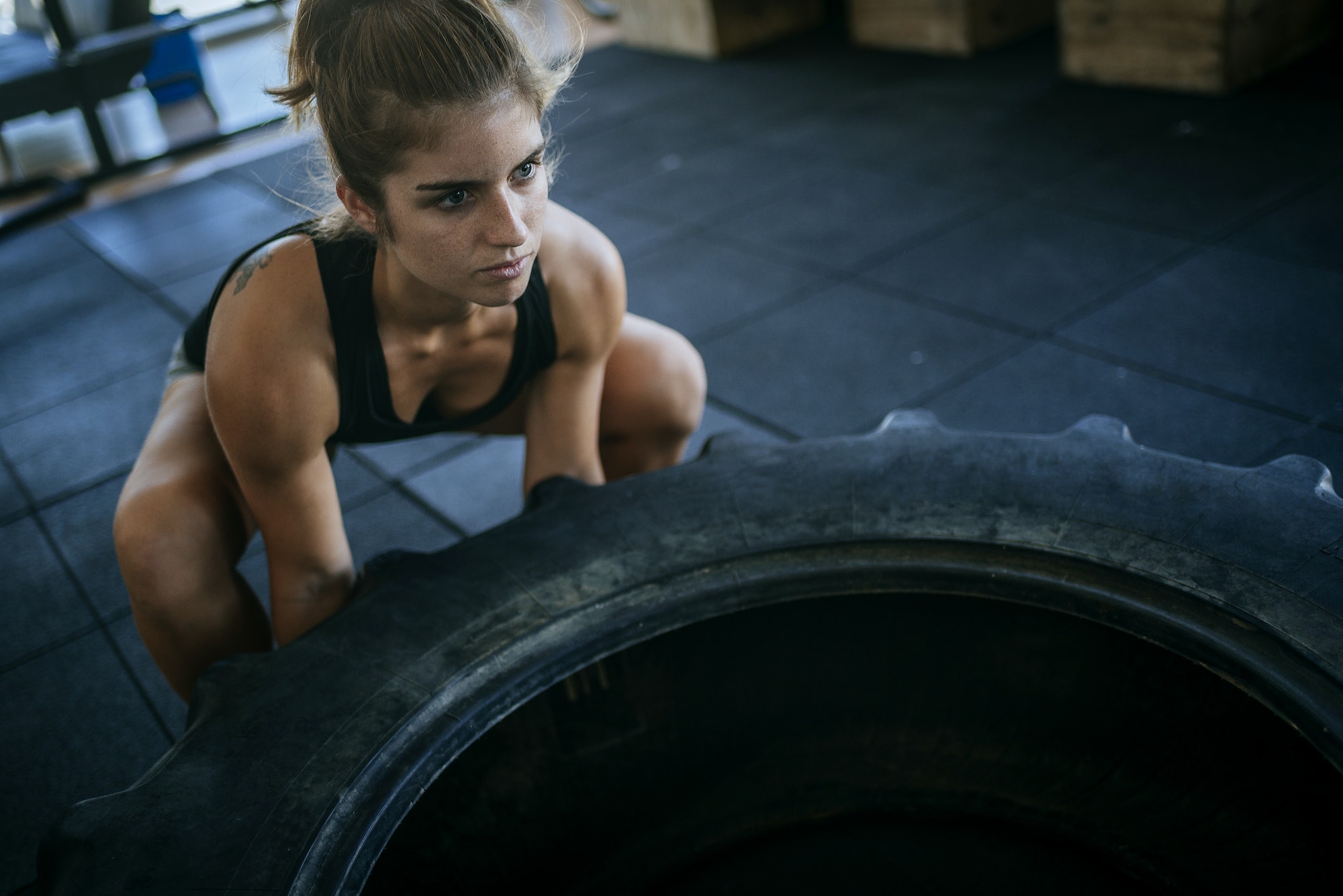 Woman exercising with a tractor tyre in gym